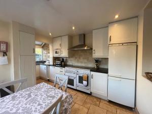 a kitchen with white appliances and a table and a table and a table at Midsomer Cottage- Spacious Victorian Cottage with parking & garden - Close to City and ring road in Oxford