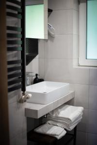 biała łazienka z umywalką i ręcznikami na półce w obiekcie Domek Pierwiosnek Ustroń w Ustroniu