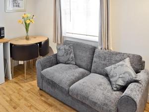 um sofá cinzento numa sala de estar com uma mesa em Baytree Cottage 1 em Birch