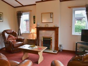 a living room with a fireplace and leather furniture at Rosella in Bridekirk