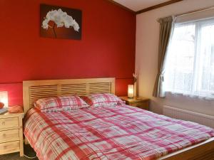 um quarto com uma cama e uma parede vermelha em Rosella em Bridekirk