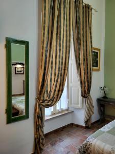 een slaapkamer met een raam met gordijnen en een spiegel bij il Rifugio dell'Artista in Passignano sul Trasimeno