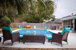 a swimming pool with chairs and a table next to it at ~NEW~1 mins to Bay~8 Mins to Beach~Private Pool~Super relaxing beach theme in Navarre