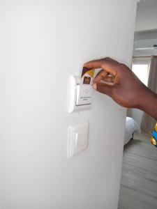 a person pressing a button on a white wall at Piccola Beach in Sassako Bégniny