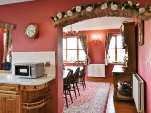 a kitchen with pink walls and a table with chairs at Ye Olde Smithy in Burythorpe