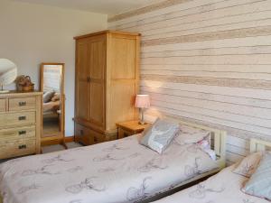 a bedroom with two beds and a wooden wall at Ye Olde Smithy in Burythorpe
