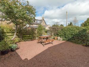 a wooden picnic table sitting in the middle of a garden at Stable Cottage in Alnwick