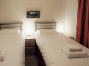 two beds in a bedroom with towels on them at Ransome Lodge in High Nibthwaite