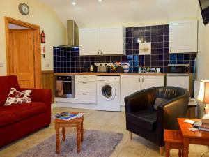 a living room with a red couch and a kitchen at Ty Bach Twt in Llangeitho