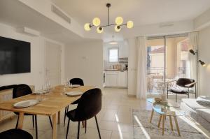 ein Wohnzimmer mit einem Tisch, Stühlen und einem Sofa in der Unterkunft Magnifique et lumineux 3 pieces A2B238 in Cannes