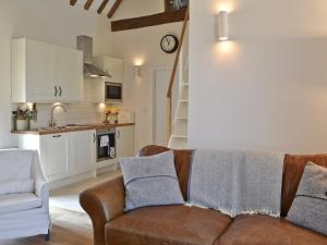 a living room with a couch and a kitchen at Fig Cottage in Brabourne