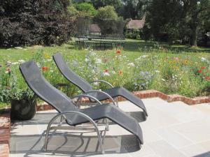 two black chairs sitting next to a field of flowers at Fig Cottage in Brabourne