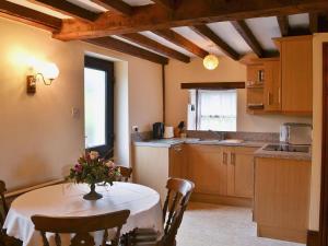 a kitchen with a table with a vase of flowers on it at Ellarbeck Cottage in Caldbeck