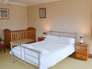 een slaapkamer met een bed met witte lakens en een wieg bij Windways in Port Erin