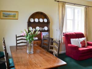 una sala da pranzo con un vaso di fiori su un tavolo di Paddock Cottage ad Alnwick