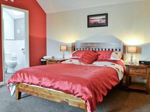 a bedroom with a large bed with red walls at West Rose Barn in Pendine