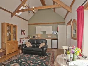 a living room with a leather chair and a kitchen at Timberway in Okehampton