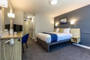 Dormitorio con cama, escritorio y TV en Days Inn Hotel Sedgemoor, en Rooks Bridge