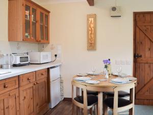 a kitchen with a table with two chairs and a microwave at Lower Mill Barn in Nantgaredig