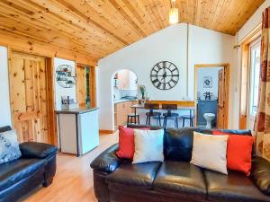 a living room with a leather couch and a kitchen at Hooked Rise Holiday Lodge in Dunkeswell