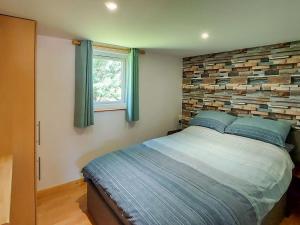 a bedroom with a bed and a brick wall at Hooked Rise Holiday Lodge in Dunkeswell