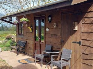 a cabin with chairs and a table in front of it at Hooked Rise Holiday Lodge in Dunkeswell