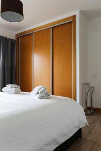 um quarto com uma grande cama branca e uma cabeceira em madeira em Carmona G em São Martinho do Porto