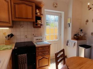 a kitchen with a stove and a table and a window at Laurel Cottage in Sway