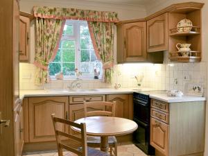 eine Küche mit Holzschränken, einem Tisch und einem Fenster in der Unterkunft Laurel Cottage in Sway