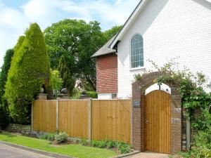 una casa con una puerta de madera y una valla en Laurel Cottage en Sway