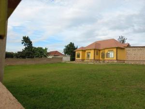 una casa gialla in un cortile con un prato verde di Cheerful Villa Nyamata a Kayenzi