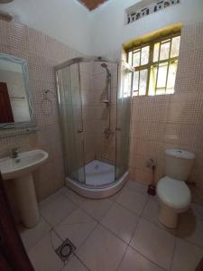 a bathroom with a shower and a toilet and a sink at Cheerful Villa Nyamata in Kayenzi