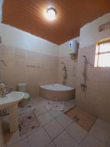 y baño con bañera, aseo y lavamanos. en Cheerful Villa Nyamata, en Kayenzi