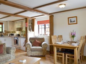 a living room with a table and chairs and a kitchen at Stable Cottage in East Meon