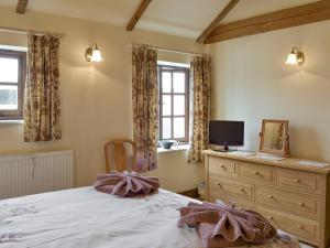 um quarto com uma cama, uma televisão e janelas em Stable Cottage em East Meon