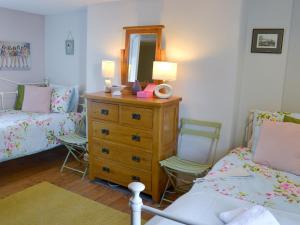 a bedroom with two beds and a dresser with a mirror at Providence Cottage in Turnchapel