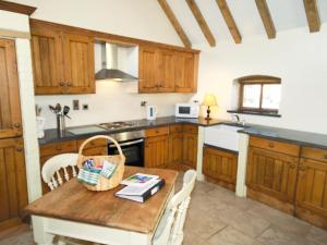 een keuken met houten kasten en een houten tafel bij Grooms Cottage - E5398 in Dunstall