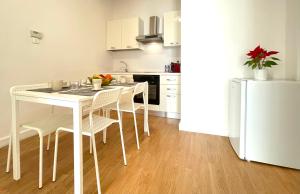 uma cozinha com uma mesa e cadeiras brancas e um frigorífico em Civico40Apartment em Lecce