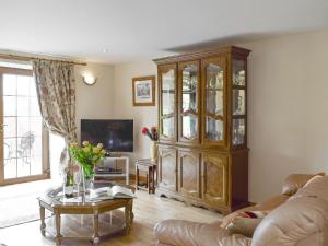 a living room with a large wooden cabinet and a table at The Stables - Uk5532 in Kepculloch