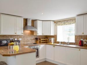 a kitchen with white cabinets and a counter with oranges on it at The Stables - Uk5532 in Kepculloch