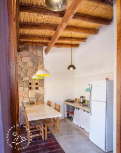 a kitchen with a wooden table and a refrigerator at Cabañas El Mirador de Tilcara in Tilcara