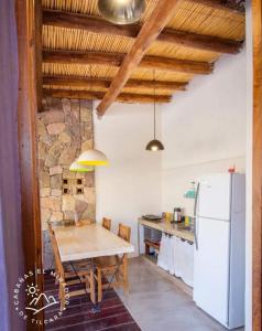 cocina con mesa de madera y nevera en Cabañas El Mirador de Tilcara en Tilcara