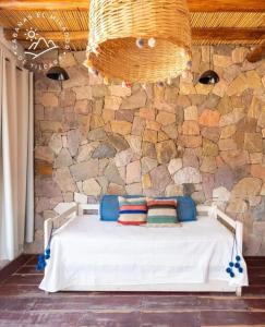 Cama en habitación con pared de piedra en Cabañas El Mirador de Tilcara en Tilcara