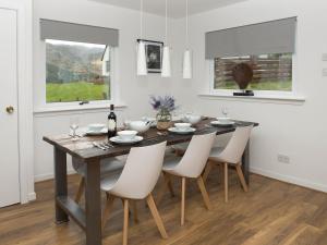 a dining room with a wooden table and white chairs at Rosdail in Inverinate