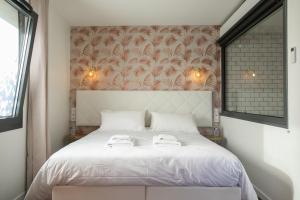 1 dormitorio con 1 cama blanca y 2 toallas en Le Maleville - Balnéo & Ascenseur, en Périgueux