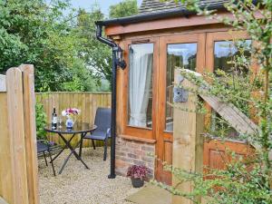 a garden room with a table and a fence at Half Moon in Herstmonceux