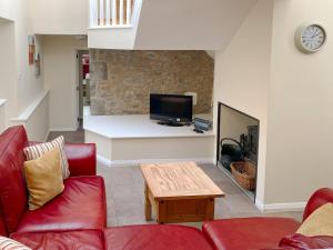 a living room with a red couch and a tv at Stable Barn - Hw7591 in Bettws-yn-Rhôs