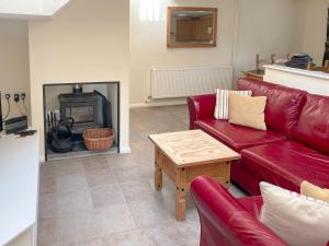 a living room with a red couch and a fireplace at Stable Barn - Hw7591 in Bettws-yn-Rhôs