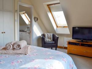 a bedroom with a bed with a television and towels at Stratton Mill in Cirencester