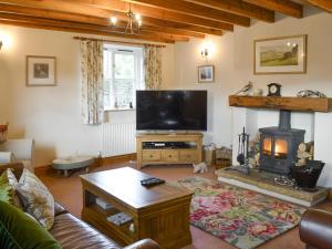 a living room with a television and a fireplace at The Old Chapel in Aysgarth